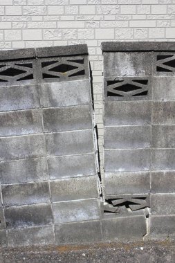 Çatlak beton duvar açık havada görünen yapısal hasarı gösteriyor.