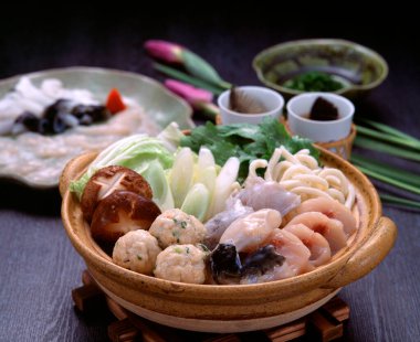 Taze deniz ürünleri ve sebzeler bambu buharlı bir sepetin içinde koyu ahşap bir masaya batırılmış soslar.