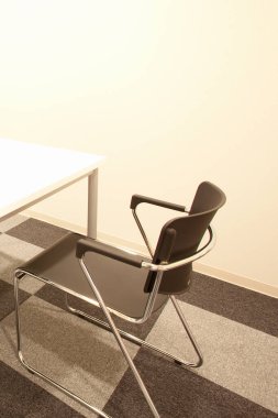 Gün ışığında minimalist bir ofiste boş sandalye ve masa.