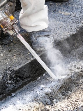 Yüksek basınçlı su jeti gün içinde bir inşaat alanında asfalt kesiyor.