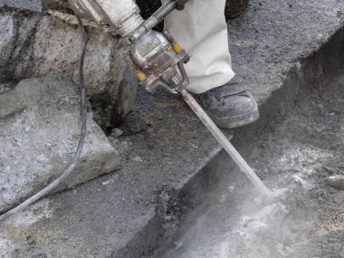 İşçi, inşaat alanında gündüz vakti beton yüzeyi temizlemek için yüksek basınçlı su jeti kullanıyor.