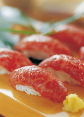 Lezzetli suşi ruloları, taze balık ve canlı renkler, rahat bir restoranda ahşap bir tabakta servis ediliyor.