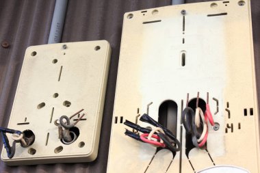 Açık havada bej montaj levhalarından çıkan elektrik kabloları.