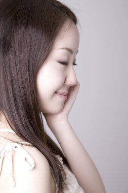 Genç ve güzel Asyalı bir kadının açık arkaplandaki yakın çekimi.