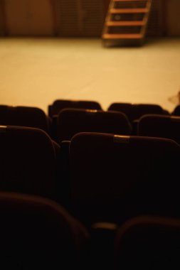 Sahneye bakan boş sinema koltukları ve görünen merdivenler.