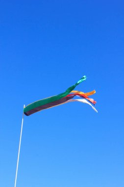 Mavi gökyüzünde uçuşan renkli rüzgarlık.