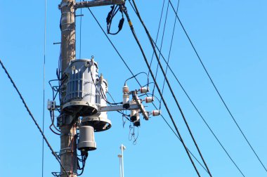 Mavi gökyüzüne karşı elektrik direği ve kablolarının düşük açılı görüntüsü 