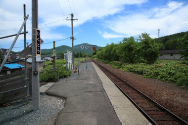 Yeşil tepelerle çevrili boş tren istasyonu platformu