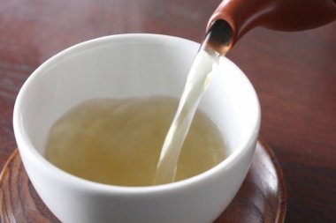 Çaydanlıktan bir fincana bitkisel çay dökme görüntüsü. 