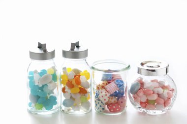 Beyaz stüdyo arka planında izole edilmiş renkli şekerli cam kavanozlar.