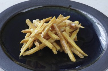 Siyah tabakta tuzlu kızarmış patates.