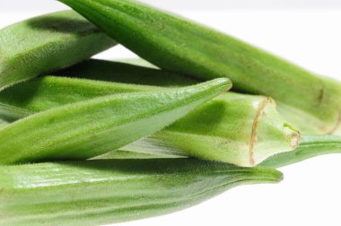 Taze yeşil bamya kabukları beyaz arkaplana karşı dizilmiş