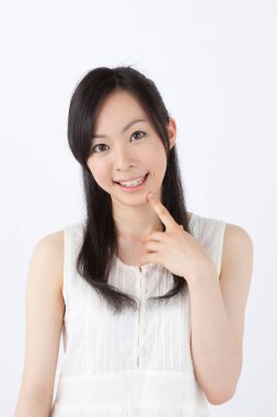 Beyaz arka planda gülümseyen genç Asyalı kadın.