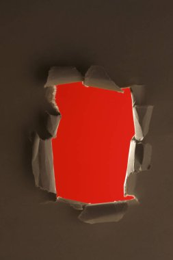 Kırmızı arkaplanda yırtık kağıtta delik    