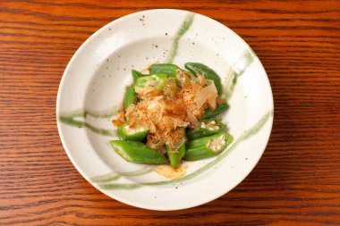 Dilimlenmiş yeşil biber ve seramik tabakta bonito taneleri.