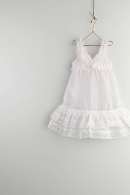 Askıda asılı beyaz bebek elbisesi.