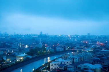 Binaları, çatıları ve nehri olan şehir manzarası.       
