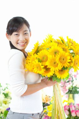 Güzel Asyalı kadın bir buket sarı çiçekle poz veriyor.