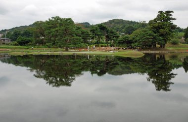 Sakin göl yeşil ağaçları yansıtıyor uzak tepeler bulutlu arka plan