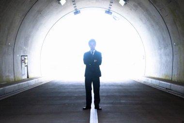 Genç Asyalı işadamı tünelde duruyor. 