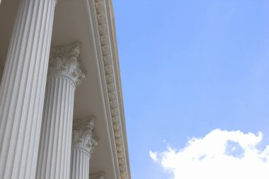 Sütunları ve mavi gökyüzü olan bir bina. 