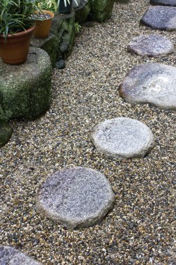Çakıl bahçesi yolu boyunca dizilmiş yuvarlak taş basamaklar.