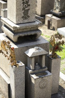 Geleneksel Japon taşlarını aydınlatan güneş ışığı mezar taşları ve adaklar