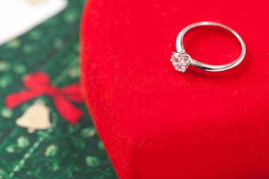 Alyans, kırmızı kalp şeklinde hediye kutusu ve noel kartı, yakın plan.             