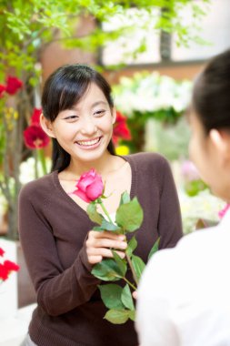 Çiçekçide müşterisi olan genç Japon kadın çiçekçinin portresi