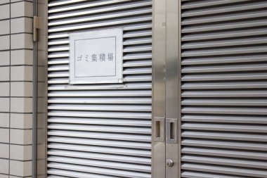 Kapalı metal kepenk kapısı. Duvarın yanında sergi levhası var.