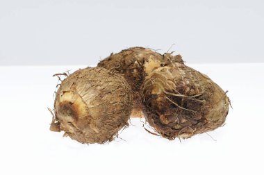 Beyaz yüzeyde üç taze taro kökü