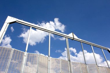 Parlak mavi gökyüzüne karşı duran metal çit yapısı