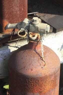 Paslı metal gaz silindiri dağınık molozların arasında dışarıda duruyor.