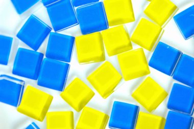 Beyaz arkaplanda mavi ve sarı plastik küpler 