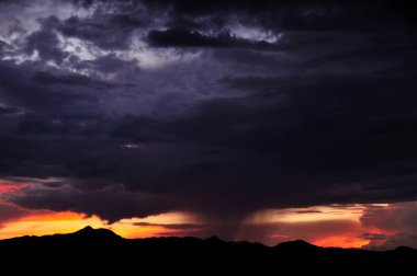 Karanlık dağların üzerinde dramatik bulutlarla dramatik gün batımı