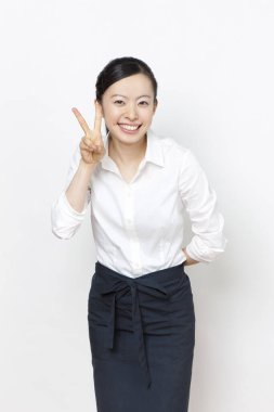 Gülümseyen Asyalı iş kadınının portresi zafer işareti gösteriyor 