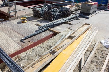 Bitmemiş inşaat sahasına saçılmış çeşitli inşaat malzemeleri.