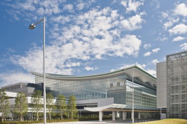 Gökyüzünü ve çevresindeki yeşilliği yansıtan modern cam bina