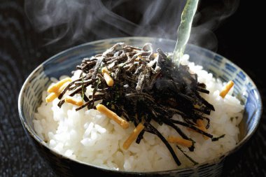 Üzerinde yosun ve baharat olan buharda pişmiş pirinç kasesi.