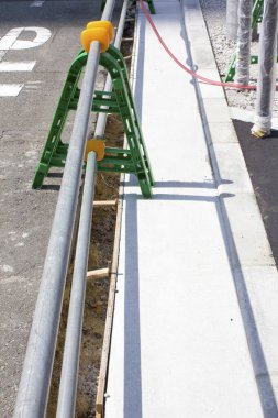 Yeni asfaltlanmış kaldırım inşaat alanının yanında çalışan metal korkuluklar.
