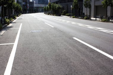 Gün ışığında boş şehir caddesi taze asfalt izleri gösteriyor