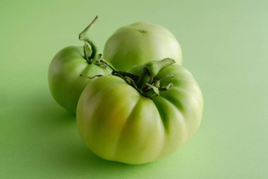 Yeşil bir yüzey üzerinde üç yeşil domates