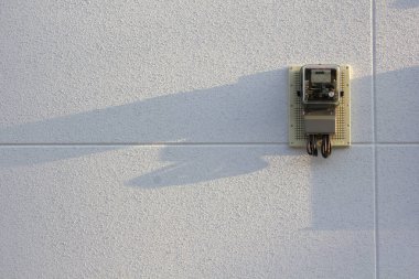 Metal kapı mandalı beyaz desenli duvar yüzeyinde uzun gölgeler bırakıyor.