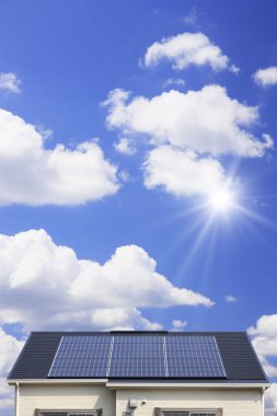 Mavi gökyüzünün önündeki evin çatısındaki güneş panelleri..