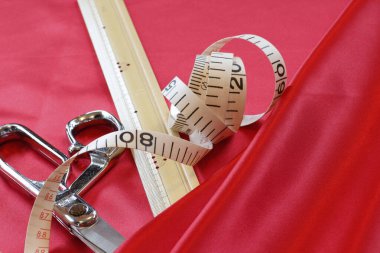 Kırmızı kumaş üzerinde makas ve ölçü bandı