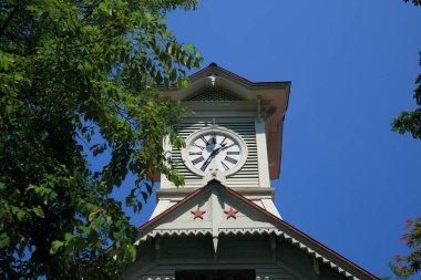 Yeşil ağaçlardaki eski saat kulesi 