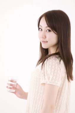 Genç ve güzel Asyalı bir kadının açık arkaplandaki yakın çekimi.