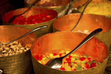 Bakır kaselerin içinde rengarenk sebzeler var.