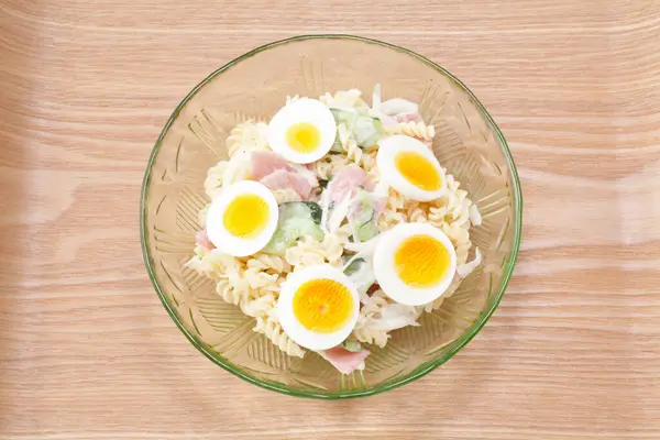 salad with boiled eggs and pasta on background, close up