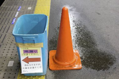 Sokağın ıslak zemininde sarı güvenlik konisi